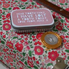 a pink and white flowered suitcase with a toothbrush on it's side