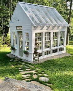 a small white house sitting on top of a lush green field