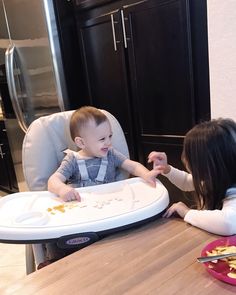 two young children sitting at a table eating food