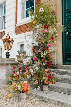 a bunch of flowers that are sitting on the ground next to some steps and a lamp