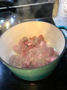 meat cooking in a pot on top of the stove with steam coming out from it