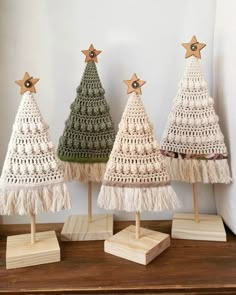 three small crocheted christmas trees on wooden bases with tassels and star decorations