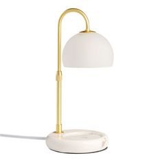 a white and gold desk lamp with a round light shade on the top of it