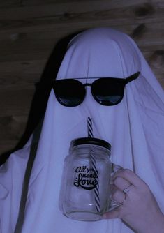 a person in a nun costume holding a jar with a candle on it and wearing sunglasses