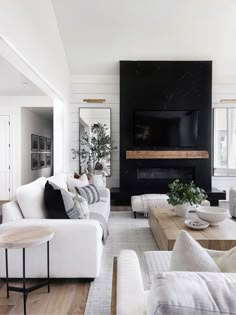 a living room filled with white furniture and a flat screen tv mounted on the wall