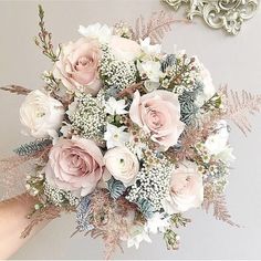 a bridal bouquet is being held by someone's hand in front of a mirror