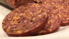 three slices of salami on a white plate