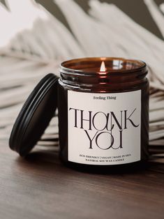 a candle sitting on top of a wooden table next to some paper and a black lid