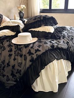 a bed with black and white ruffled bedspread, hat on the pillow