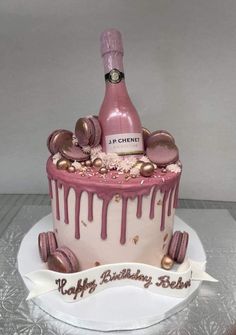 a birthday cake with a bottle of champagne on top and pink icing dripping down the side