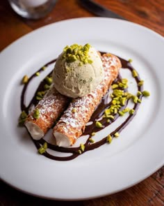 two desserts on a white plate with chocolate sauce and pistachio