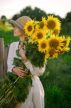 a woman is holding sunflowers in her hands