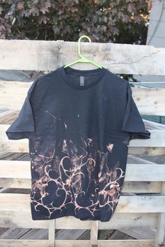 a black t - shirt hanging on a wooden fence with trees in the back ground