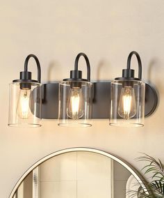 three light bathroom fixture with clear glass and black metal finish, on a white wall