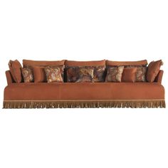 a brown couch with many pillows on it and fringe trim around the backrests