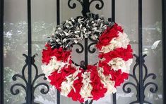 a wreath with red, white and black flowers hanging on a gate