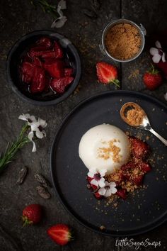 strawberries and yogurt on a black plate with spoons next to it