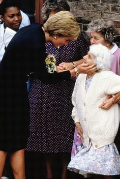 an older woman is being handed flowers by two women