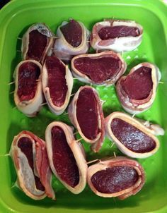 several pieces of meat on skewers in a green bowl