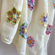 crocheted flowers on white towels hanging from the wall in front of a window