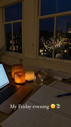 an open laptop computer sitting on top of a wooden desk next to a candle and paper