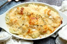 a white bowl filled with macaroni and cheese covered in herbs on top of napkins