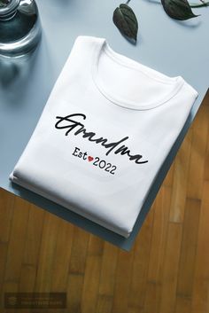 Personalized Grandma Est. white t-shirt. Please use the personalized section to write the year you would like printed on the t-shirt. *Please see listing photos for sizing info, additional color options and instructions for ordering multiples. *Care Instruction: Turn inside out and wash in cold water. Tumble dry using low heat setting. Do not dry clean. Do not iron directly on design.  *Processing And Shipping Processing 1-3 days. First Class shipping with tracking is 2-5 business days(after pro Customizable White T-shirt For Personalized Gift, Custom Print White T-shirt For Personalized Gift, Personalized Family Matching T-shirt With Custom Text, Personalized White Top With Name Print, Family Matching Custom Text T-shirt For Personalized Gift, Custom Text Family Matching T-shirt For Personalized Gift, Family Matching T-shirt With Custom Text For Personalized Gift, Personalized Name Print White Top, Personalized White Cotton Top