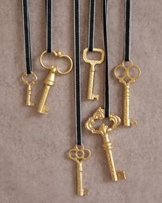 five different types of keys hanging from black cord with gold tone hardware on top and bottom