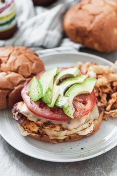 a sandwich with avocado and tomatoes on it next to some other food items