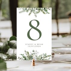 the table numbers are placed on top of each other, with greenery around them