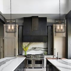 a kitchen with marble counter tops and stainless steel appliances, along with pendant lights hanging from the ceiling