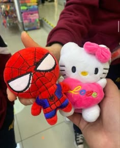 hello kitty and spiderman stuffed animals are being held by someone