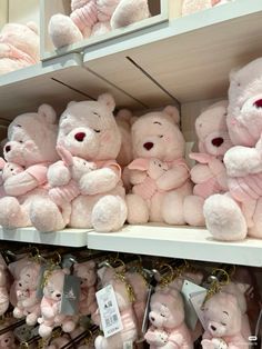 many pink teddy bears are on display for sale in a toy store, with tags attached to them