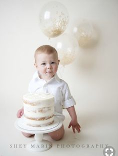 a baby sitting on the ground with a cake