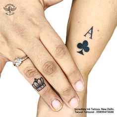 two people with matching tattoos on their arms holding each other's hands, both wearing rings