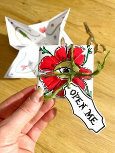 someone is holding an origami flower with the word open on it in front of some scissors