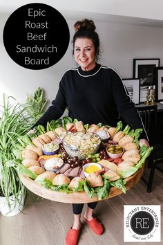 a woman standing in front of a platter full of food with the words epic roast beef sandwich board