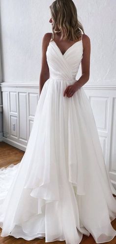 a woman in a white wedding dress standing on a wooden floor