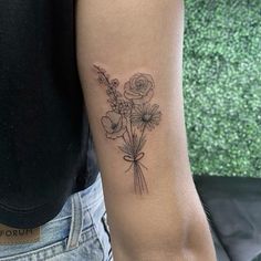 a woman with a tattoo on her arm holding a bouquet of flowers in one hand