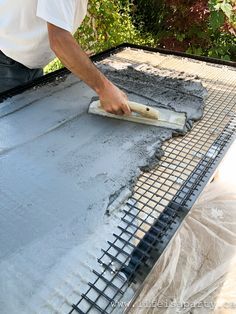 a man is laying concrete on top of a roof with a cement roller in his hand