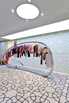 a clothing rack with clothes hanging on it in a room filled with tiled floors and white walls