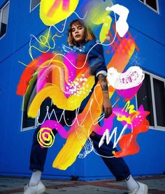 a woman is walking in front of a blue building with colorful graffiti on the wall