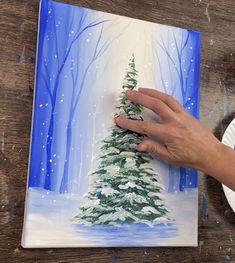 a person is painting a christmas tree on a paper plate with watercolors and acrylic paint