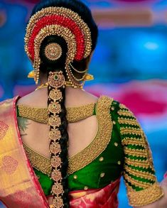 a woman in a green and red sari with an intricate braid on her head