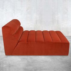 an orange couch sitting on top of a cement floor