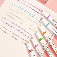 four pens are lined up next to each other on a sheet of paper with different designs