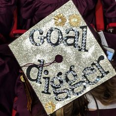 a graduate's cap that says, goal diggers on it in the middle of her graduation gown