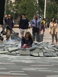 a woman sitting on the ground in front of a fire hydrant with people standing around her