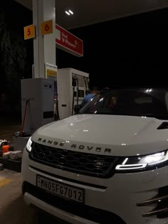 a white range rover parked at a gas station