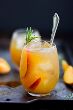 two glasses filled with orange juice and garnished with fresh herbs on the rim